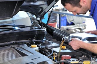 Mechanic adding oil to vehicle
