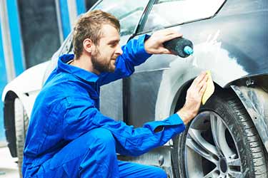 man repairing damaged car