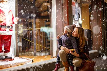 Mother and daughter looking in christmas decorated store window