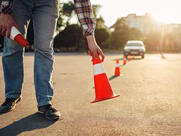 man putting pylons down for defensive driving practice