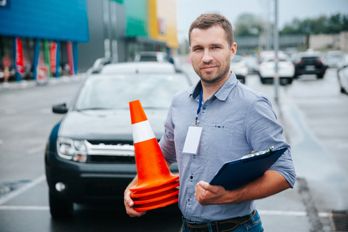 Male driving teacher holding pylons