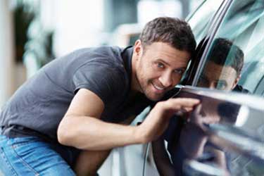 Man inspecting automobile for scratches