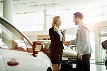 Man shaking woman's hand at a car dealership