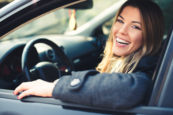 happy female driver sitting inside car