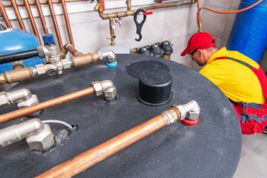 hot water tank repair man wearing yellow and red