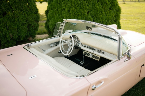 pastel pink vintage car parked near trees