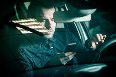 male driver looking down on phone