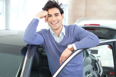 man standing behind car door with a smile