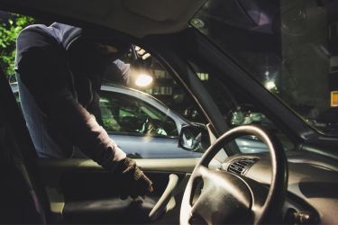 Man breaking into a automobile through the door