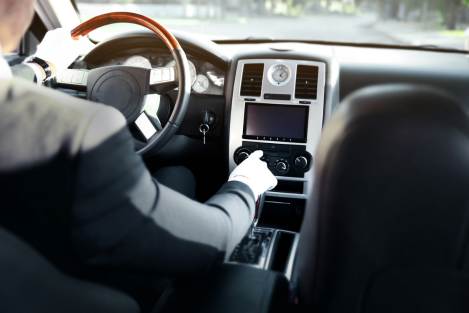 man wearing suit changing radio stations inside car