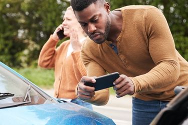 Man taking photos of car damage from an accident