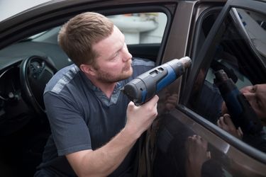 man tinting windows on a car