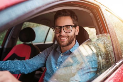 man with glasses driving red car