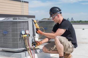 man kneeling beside HVAC system