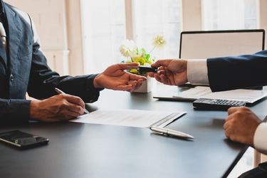 car kets behind handed over to a buyer from salesman in suit
