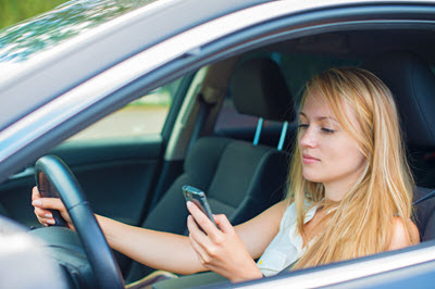 blonde woman looking at her phone while driving