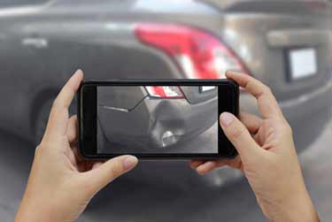 Damaged rear bumper of a car on smartphone