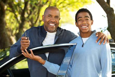 Teenage boy with father by a call holding car key