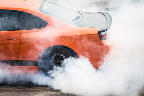 Orange car stunt driving doing a burnout