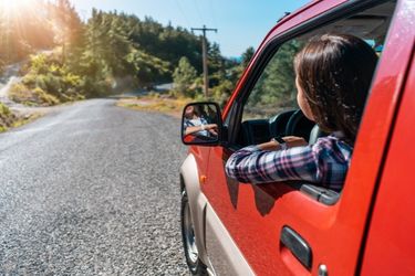 red car driving on country road