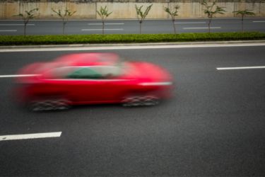 red car driving fast on road