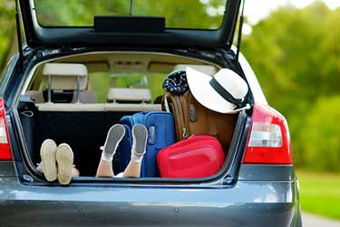 Open hatch of SUV with luggage and kids playing in it