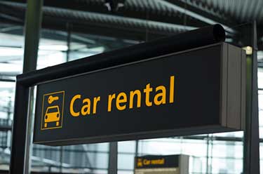 Black sign with orange text saying rental car