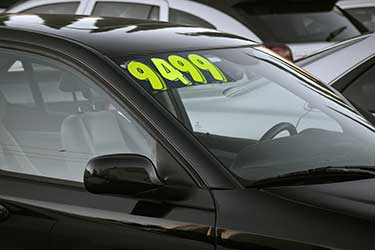 Black car for sale with lime green cost on window