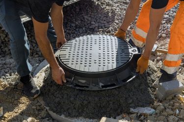 two men lifting a septic tank lid