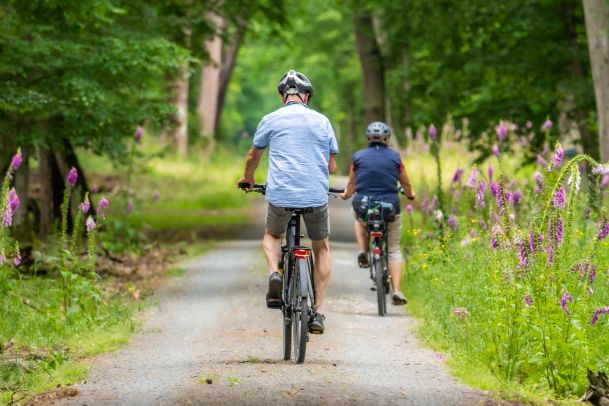 couple riding bike on a trail with wildflowers