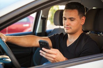 Man in black shirt on his phone while driving