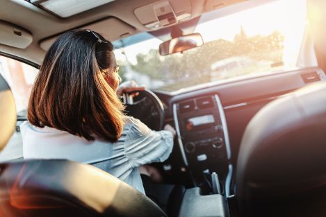 woman with dark hair driving a car on a sunny day