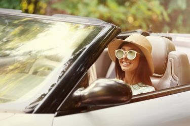 woman driving convertable with hat