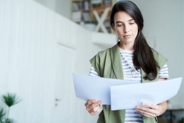 woman wearing a green vest, reviewing insurance OPCF documents