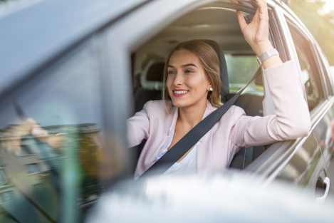 woman driving a black car wearing a pink blazer