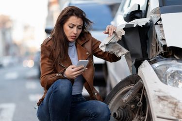 woman with brown hair calling in accident on road