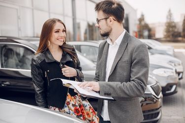 woman shopping at car dealership with salesman