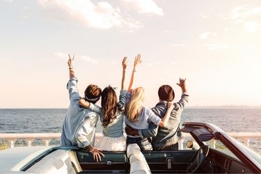 Group of young people outside car at the beach